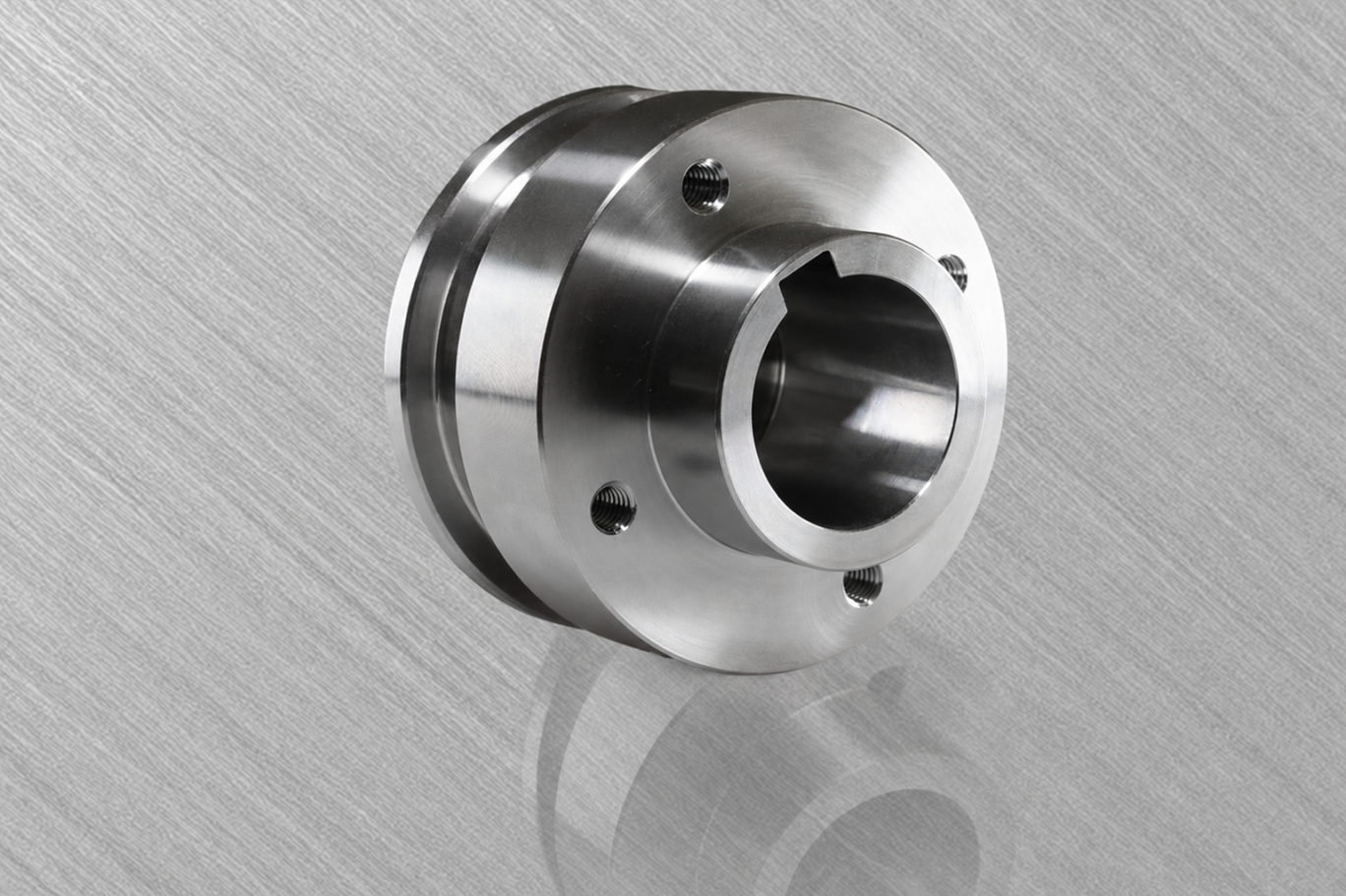 Zylindrischer Metallteil mit mittlerer Öffnung und Montagebohrungen.